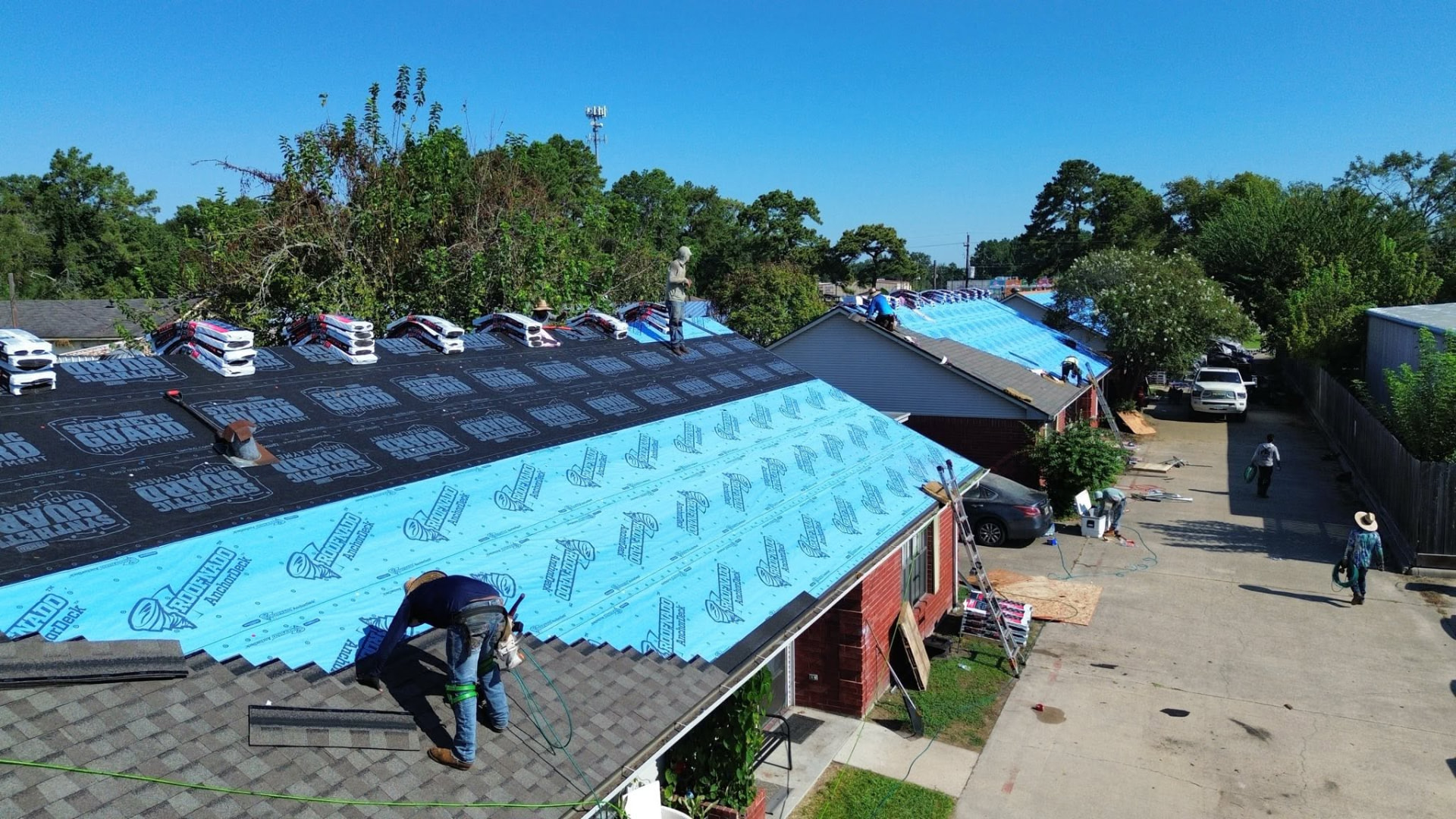 Crew rolling synthetic underlayment across a residential roof deck